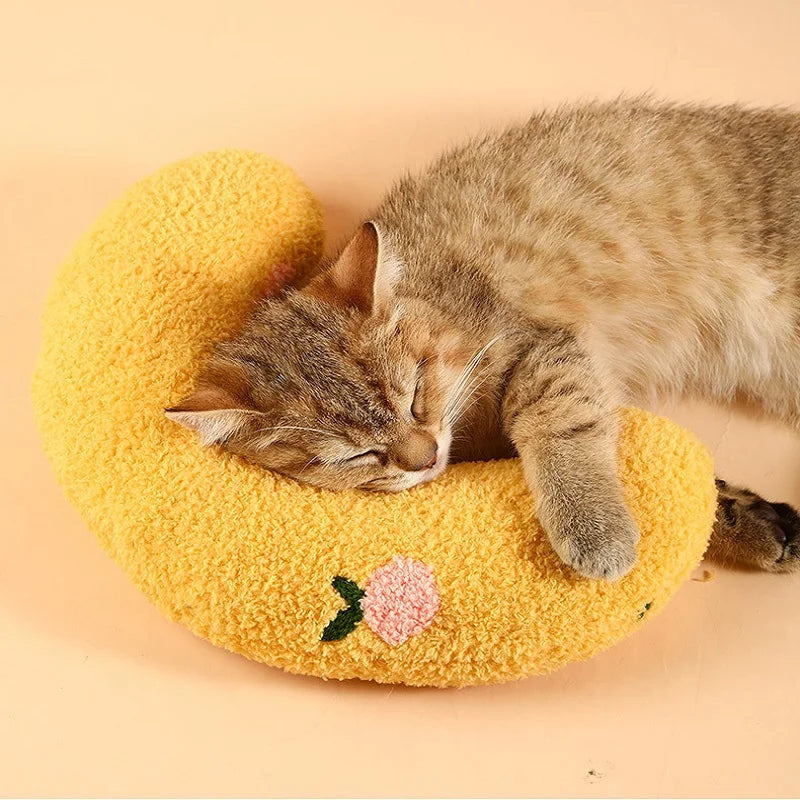 Tabby cat asleep on the yellow half-moon pillow with an embroidered flower